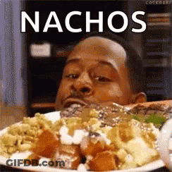 A Man Is Eating A Plate Of Food With Nachos Written On It . GIF