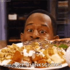 A Man Is Eating A Plate Of Food With The Words `` Happy Thanksgiving '' Written On It . GIF