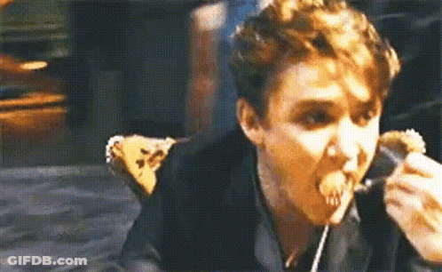 A Man Is Eating A Sandwich With A Fork And Spoon . GIF