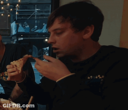A Man Is Eating A Slice Of Pizza While Wearing A Shirt That Says " Super Radio " GIF
