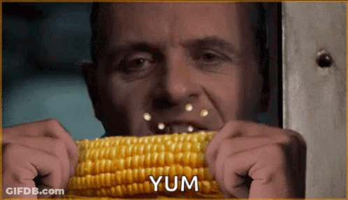 A Man Is Eating Corn On The Cob With The Word Yum In The Corner GIF