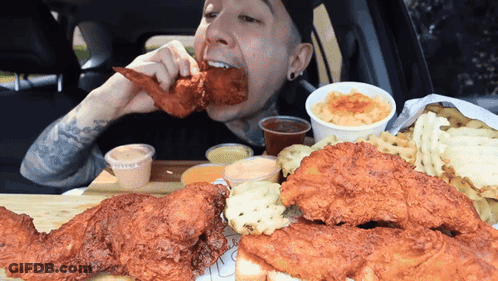 A Man Is Eating Fried Chicken And Macaroni And Cheese GIF
