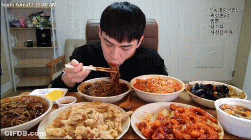 A Man Is Eating Noodles With Chopsticks At A Table With Bowls Of Food And A Time Of 12:35:40 Am GIF