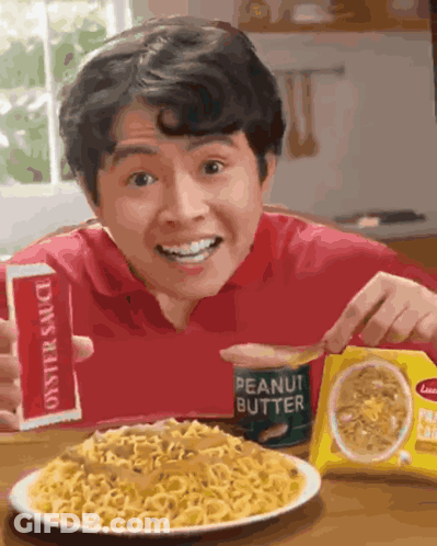 A Man Is Eating Noodles With Peanut Butter Sauce GIF