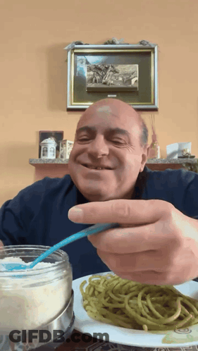 A Man Is Eating Spaghetti With A Spoon And Smiling GIF