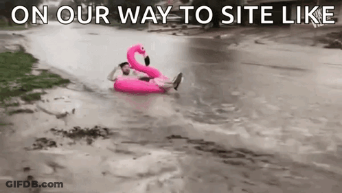 A Man Is Floating On Top Of A Pink Flamingo Float In A Flooded River . GIF