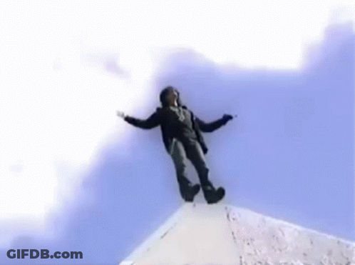 A Man Is Flying Through The Air In Front Of A Large Building GIF
