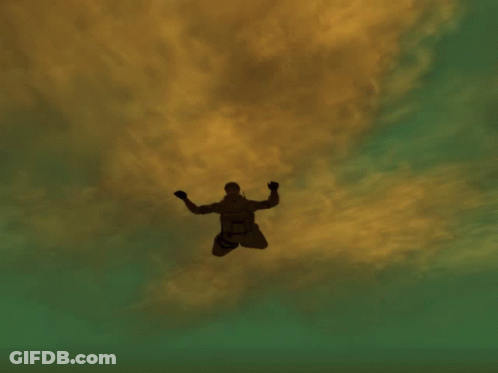 A Man Is Flying Through The Air In Front Of A Very Tall Building GIF