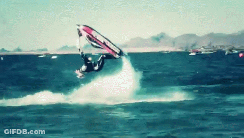 A Man Is Flying Through The Air While Riding A Wave On A Surfboard GIF