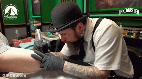 A Man Is Getting A Tattoo On Someone 'S Leg In A Paramount Network Tattoo Studio GIF