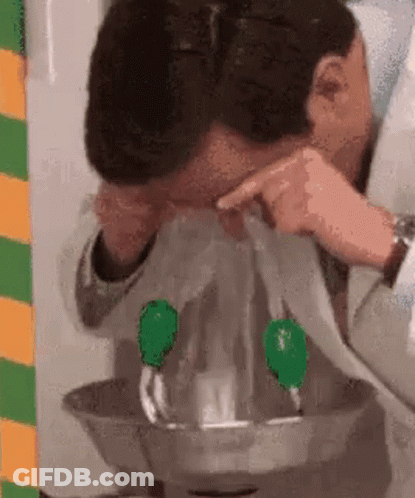 A Man Is Getting His Eyes Rinsed With Water From A Faucet . GIF