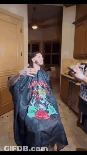 A Man Is Getting His Hair Cut By A Barber Wearing A Black Cape That Says I 'M A Freak GIF