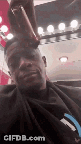 A Man Is Getting His Hair Cut In A Salon . GIF