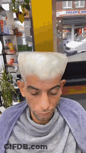 A Man Is Getting His Hair Dyed In A Barber Shop With A Sign In The Background That Says Teleport GIF