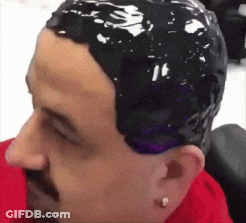 A Man Is Getting His Hair Dyed In A Salon . GIF