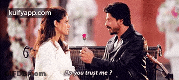 A Man Is Giving A Rose To A Woman Who Is Sitting On A Bench . GIF