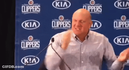 A Man Is Giving A Speech In Front Of A Kia Clippers Banner GIF