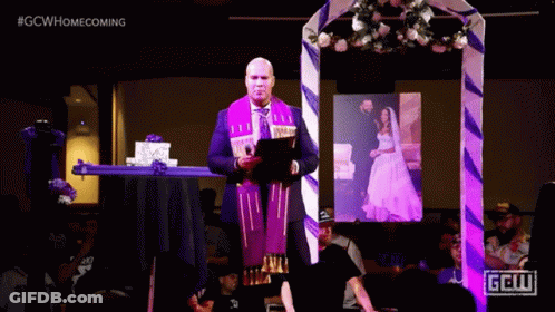 A Man Is Giving A Speech In Front Of A Picture Of A Bride And Groom And A Sign That Says Gcw GIF