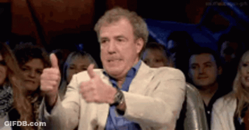 A Man Is Giving A Thumbs Up In Front Of A Crowd . GIF