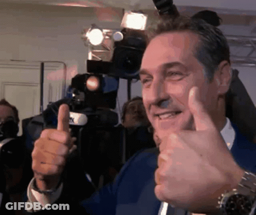 A Man Is Giving A Thumbs Up Sign In Front Of A Camera GIF