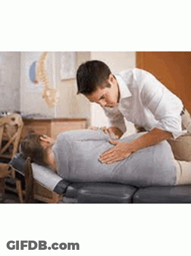 A Man Is Giving A Woman A Massage On A Table In A Room . GIF