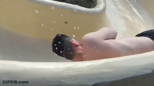 A Man Is Going Down A Water Slide At A Water Park . GIF