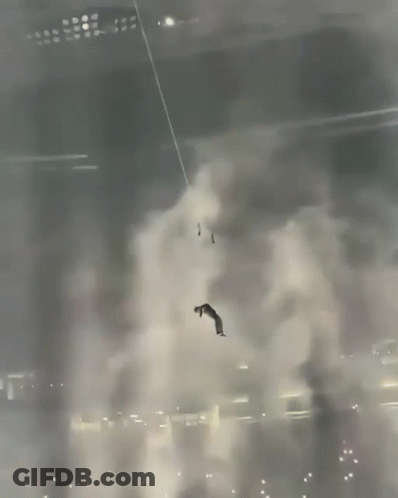 A Man Is Hanging From A Rope In A Dark Room GIF