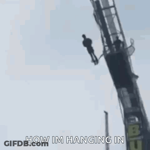 A Man Is Hanging Upside Down From A Bungee Ride . GIF
