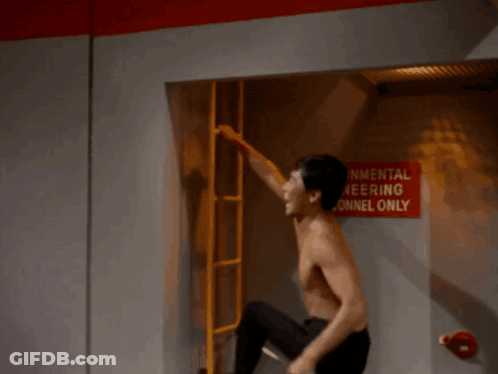 A Man Is Hanging Upside Down In Front Of A Sign That Says " Cowards " GIF