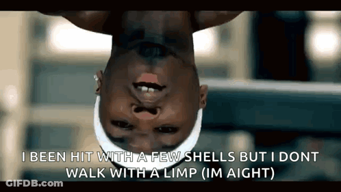 A Man Is Hanging Upside Down With A Few Shells On His Face . GIF