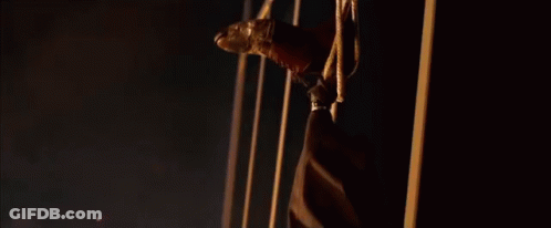 A Man Is Hanging Upside Down With A Golden Mask On His Face . GIF