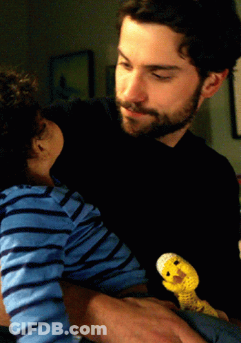 A Man Is Holding A Baby And A Stuffed Animal GIF