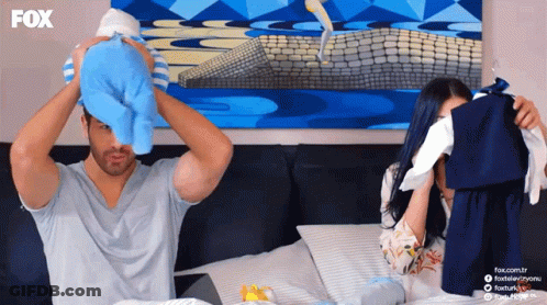 A Man Is Holding A Baby And A Woman Is Holding Clothes In Front Of A Fox Advertisement GIF