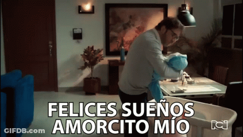 A Man Is Holding A Baby In A Living Room And The Words Felices Suenos Amorcito Mio Are Above Him GIF