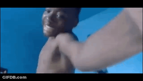 A Man Is Holding A Baby In A Swimming Pool . GIF
