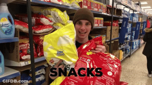 A Man Is Holding A Bag Of Snacks In A Store Aisle GIF
