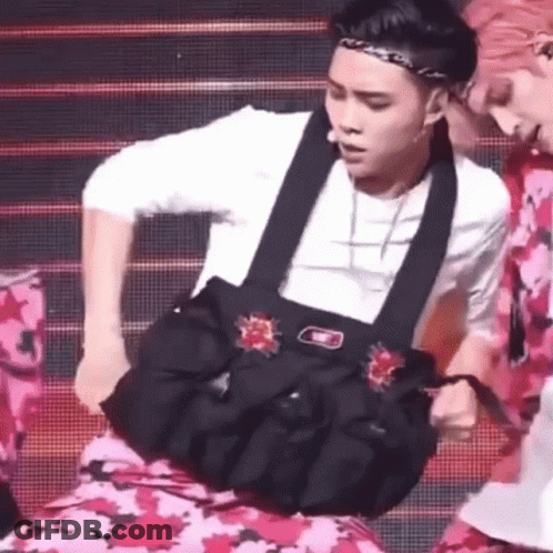 A Man Is Holding A Bag On His Stomach While Dancing On A Stage . GIF