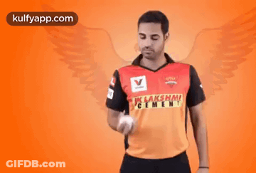 A Man Is Holding A Ball In His Hand And Wearing A Shirt That Says ' Lakshmi Cement ' On It . GIF