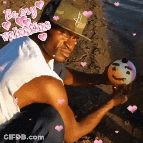 A Man Is Holding A Ball With A Face On It And The Words Be My Valentine Surround Him GIF