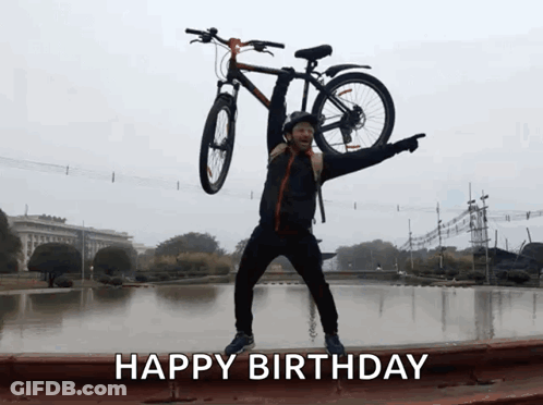 A Man Is Holding A Bicycle Over His Head And The Words Happy Birthday Are Below Him GIF