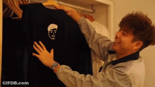 A Man Is Holding A Black Shirt With A Face On It GIF
