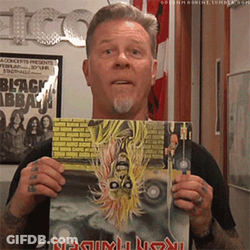 A Man Is Holding A Book That Says Metallica On It GIF