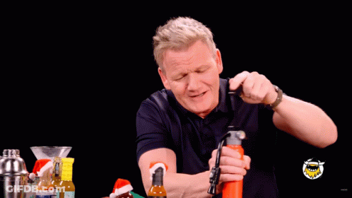 A Man Is Holding A Bottle In His Mouth And Spraying It With His Mouth GIF