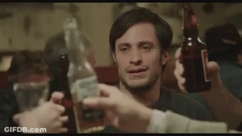 A Man Is Holding A Bottle Of Beer And A Bottle Of Tequila While A Group Of People Toast Him . GIF