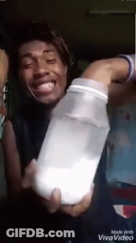 A Man Is Holding A Bottle Of Milk In His Hands . GIF