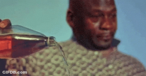 A Man Is Holding A Bottle Of Soda And Pouring It On His Face . GIF