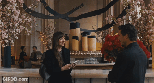 A Man Is Holding A Bouquet Of Red Flowers And A Woman Is Holding A Cell Phone GIF