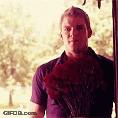 A Man Is Holding A Bouquet Of Red Flowers GIF