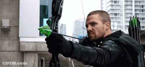 A Man Is Holding A Bow And Arrow With A Green Arrow . GIF