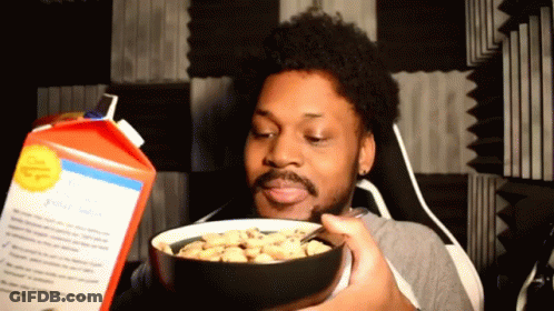 A Man Is Holding A Bowl Of Cereal In Front Of A Carton Of Cereal GIF